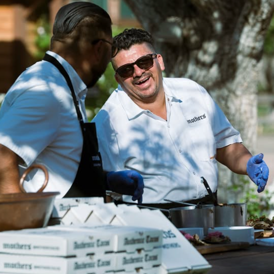 Mothers tacos team serving food at an outdoor event.